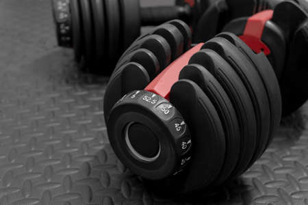 Adjustable weight dumbbell in plastic polymer material on black rubber floor.Users can choose the weight of the exercise program as needed for bodybuilding.の写真素材