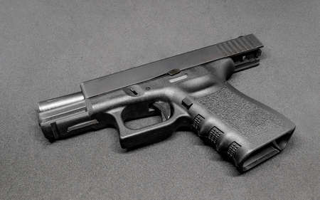 9mm pistol in locking slide placed on black floorの写真素材