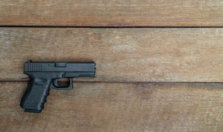 Black steel polymer semi-automatic 9mm pistol on wooden background with Copy Space