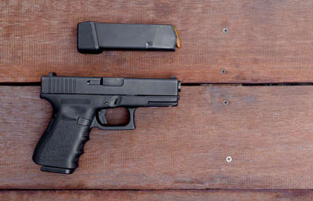 Black semi-automatic 9mm pistol and magazine on wooden background with Copy Spaceの写真素材