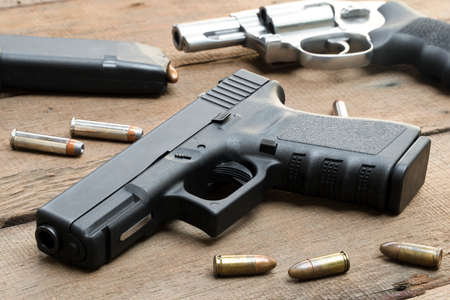 9mm pistol, .357 magnum revolver, bullets and ,magazines on wooden tableの写真素材