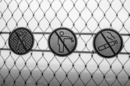 Black and white prohibiting signs on the grid 001の写真素材