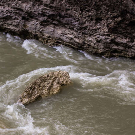 a large boulder in a mountain river lapped faster flowの写真素材