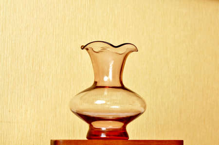 Transparent vase of artsy forms against a light brown backgroundの写真素材