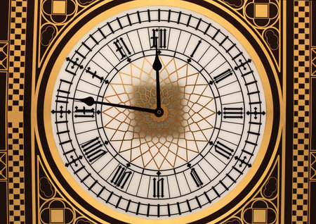 Dial with roman numerals and black clock hands on a golden backgroundの写真素材