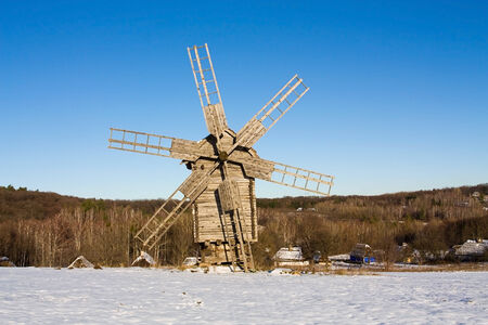 Wooden flour mill on a snowy hill on a sunny winter dayの写真素材