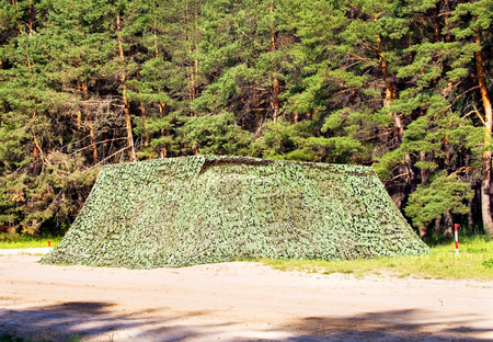 Camouflaged military object at the roadside in the forestの写真素材
