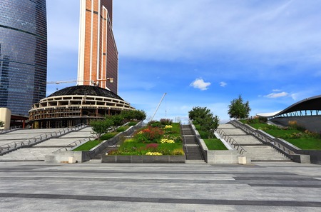 Tiered staircase with beautiful flowerbeds on the background of large-scale constructionの写真素材