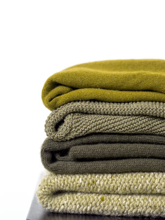 Careful stack of green colors woolen and cashmere sweaters on white background. capsule wardrobe.
