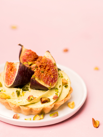 Delicious tart with fresh figs and pistachios on pink pastel backgroundsの写真素材