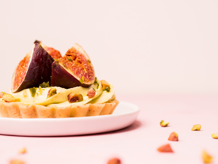 Delicious tart with fresh figs and pistachios on pink pastel backgroundsの写真素材