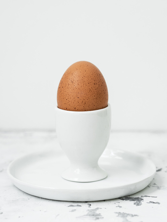 Soft-boiled egg in eggcup on white tableの写真素材