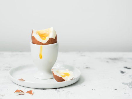 Soft-boiled egg in eggcup with yolk on white stone table.の写真素材