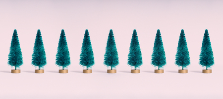 Small artificial Christmas trees on pink pastel  background. Minimal style. Christmas and New Year concept.の写真素材