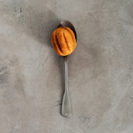 Close view of a cookies in the shape of walnut with condensed milk on vintage spoon on a concrete...