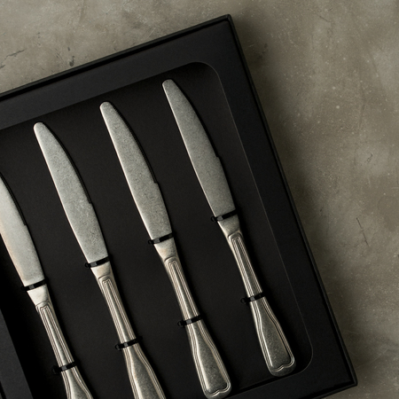 Top view of silver collection of knives in a black box on a gray concrete backgroundの写真素材