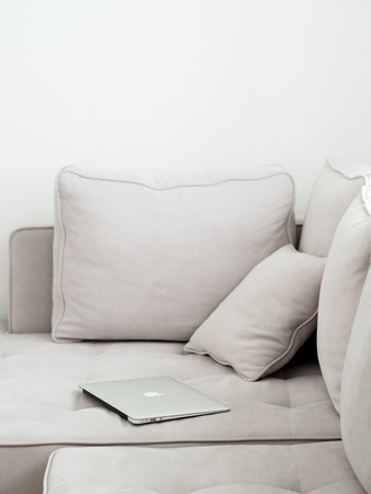 Open laptop lying on a gray sofa. Minimalistic style in a light key. Side view.の写真素材