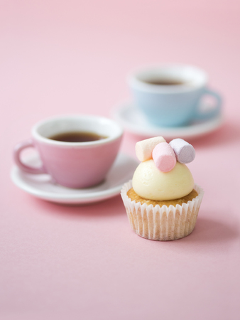 Colorful coffee cups and cupcakes with marshmallows on pink background.の写真素材