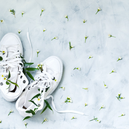 Top view of white gumshoes with fresh flowers on grey backgroundの写真素材