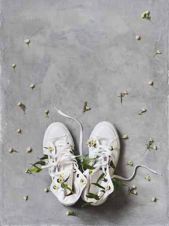 Spring concept of white sneakers with white flowers inside on concrete background.の写真素材
