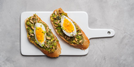 Whole-grain toasts plated avocado with eggs, fresh mini herbs, sunflower seeds and sprinkled black...