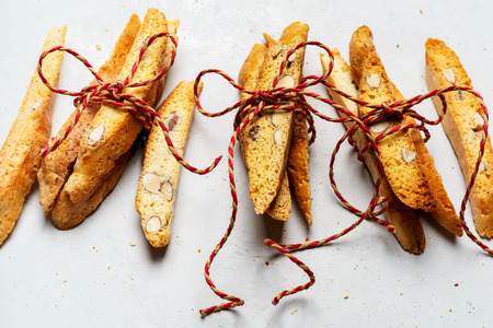 Biscotti-traditional Italian almond dessert tied with a rope of three pieces on a light surface with a copy space for the text, vertical composition.の写真素材