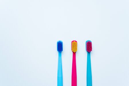 Colorful tooth brushes with bright color bristles on a light pastel blue background. Dental tools with empty space for text for  your mockup.の写真素材