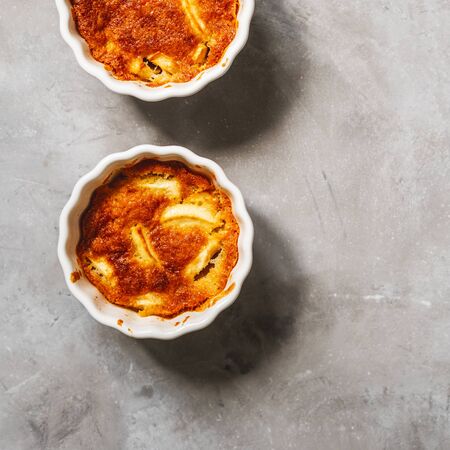 Fruit Apple pudding cake in porcelain white bakeware on grey concrete background with copy space for recipe.の写真素材