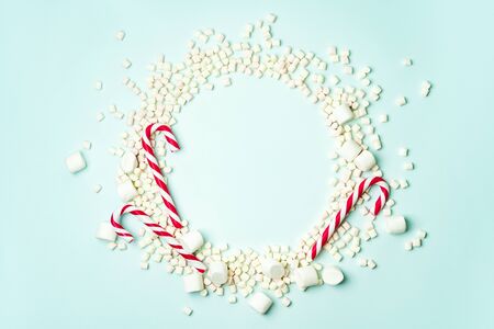 Christmas layout with candy cane and different sizes marshmallows on a turquoise background in the form of a circle shape. Concept for new year postcard with space for text.の写真素材