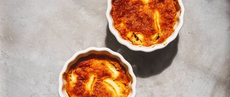 Fruit Apple pudding cake in porcelain white bakeware on grey concrete background with copy space for recipe.の写真素材