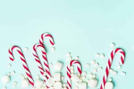 Christmas layout of frame of candy cane and marshmallows on a turquoise background with copy space . New year greeting card.の写真素材