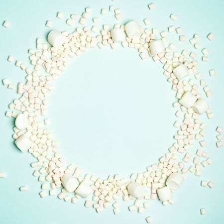 Christmas layout with candy cane and different sizes marshmallows on a turquoise background in the form of a circle shape. Concept for new year postcard with space for text.の写真素材