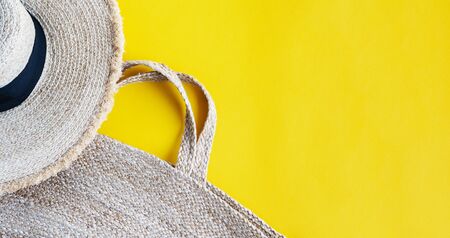 Straw hat, eco friendly wicker bag, sunglasses, monstera branches over yellow background with space for text, top view, wide composition. Summer vacation fashion, holiday concept. Beach accessories.の写真素材