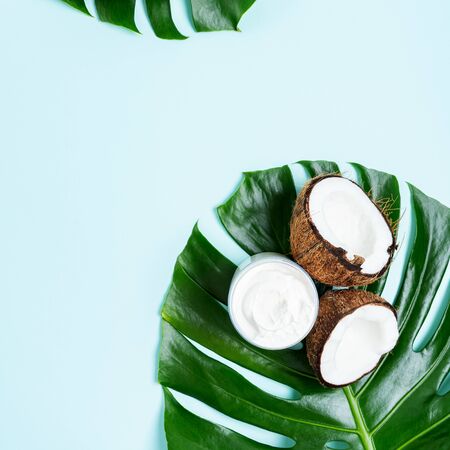 Organic healthy Coconut butter cream in jar with fresh coconut pieces on palm leaves on turquoise background with copy space. Exotic botanical concept for cosmetic, spa, perfume, aroma and health care products.の写真素材