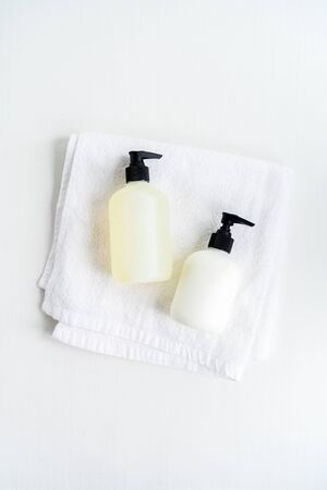 Set of Bottles with organic body care cosmetic products on white fluffy towels on a light background. Concept of SPA branding mock-up.の写真素材