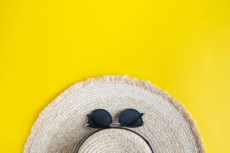 Eco friendly wicker straw hat with sunglasses over yellow background with space for text, top view, wide composition. Summer vacation fashion, holiday concept. Beach accessories.の写真素材