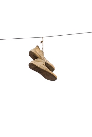 A pair of old sneakers hanging from a cable, isolated on whiteの写真素材