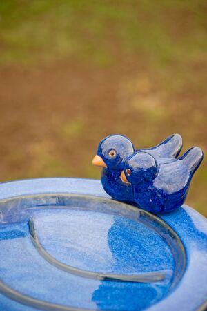 Ornamental blue bird bath with two fake birds in a public placeの写真素材