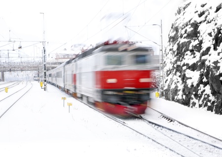 Red train in blurred motion approaching a stationの写真素材