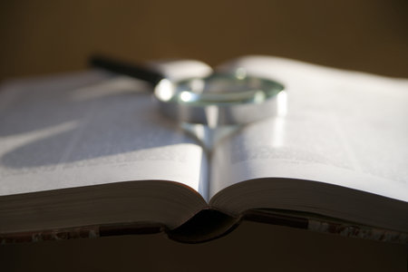 Close up of open book with magnifying glass