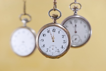 Three vintage pocket watches with golden backgroundの写真素材