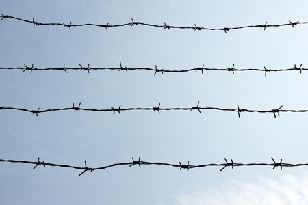 Silhouette of barbed wire on blue skyの写真素材