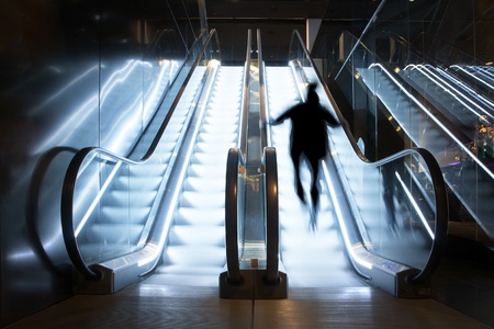 A person going up brightly lit escalatorの写真素材