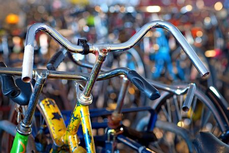 Close up of handles of old tatty yellow bike in big bicycle parkの写真素材