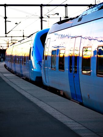 Blue commuter train in evening light at stationの写真素材