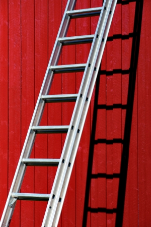 Metal ladder with shadow on red wooden wallの写真素材