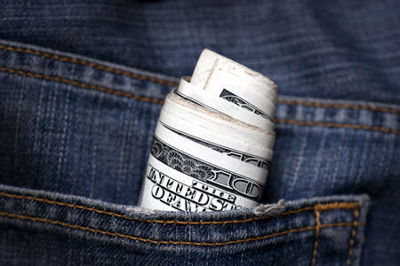 roll of hundred dollar bills in jeans pocketの写真素材