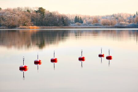 Red buoys in calm water on beautiful winter dayの写真素材