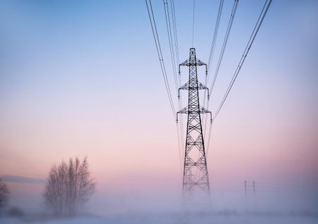 Electricity pylon in heavy fog at sunset in winter