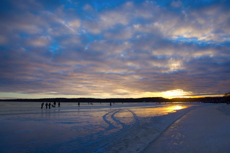 Public ice skating on lake at sunset